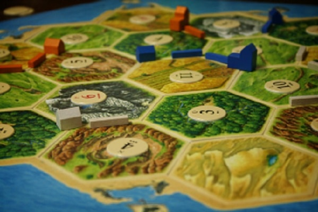 Catan Basic Board Game. Different cardboard islands and game parts shown. Affordable rental with BIYU.