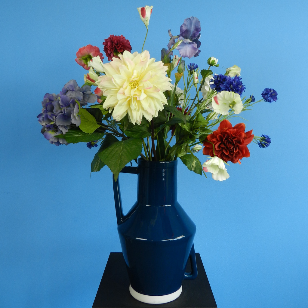 Huur dit prachtige kunstbloemen boeket in blauwe vaas voor jouw evenement bij BIYU. Foto van blauwe witte en roze bloemen. Perfect als decoratie voor feesten en bruiloften.