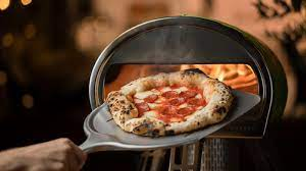 Gozney Roccbox Pizza oven met pizza op pizzaschep uit oven makkelijk en goedkoop huren bij BIYU