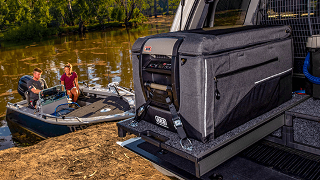ARB Portable Electronic Freezer outside in nature next to a boat on a river. Affordable rental with BIYU.