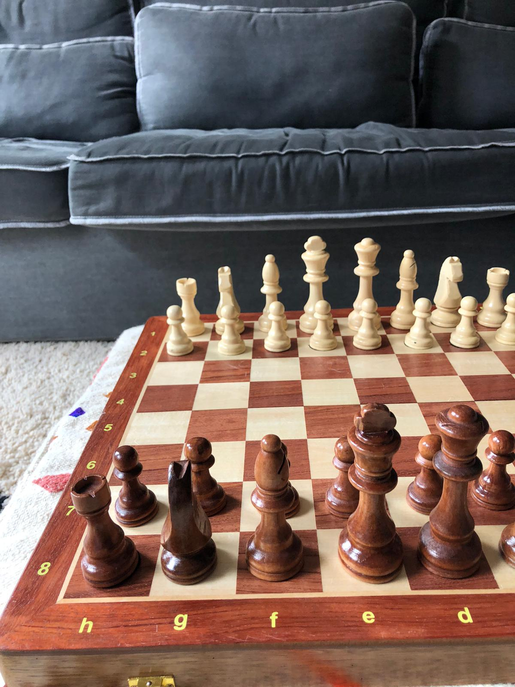 Wooden Chessboard with chess figures in start position in a living room. Affordable rental with BIYU.